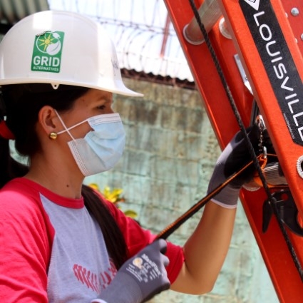 Yasin Baltodano, in mask, gloves, and hard hat, sets up a ladder